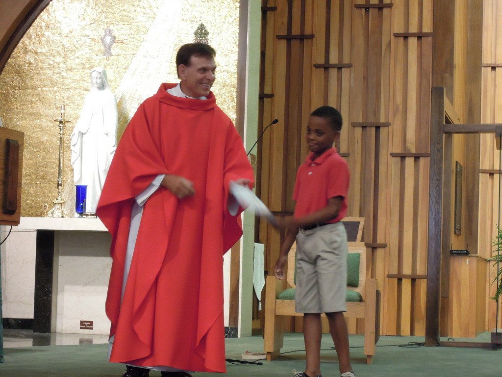 Pastor handing paper to student during Catholic mass